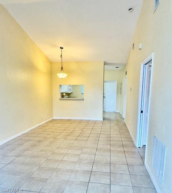 Tiled spare room with lofted ceiling and baseboards