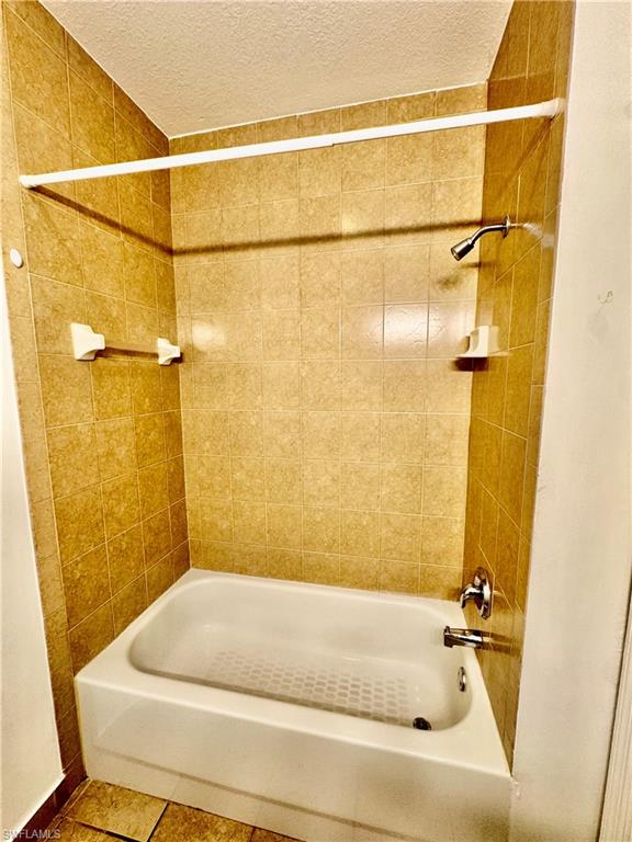 Full bathroom featuring bathtub / shower combination, tile patterned flooring, and a textured ceiling