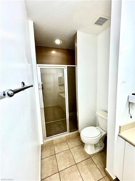Full bathroom with light tile patterned flooring, a stall shower, vanity, and a textured ceiling