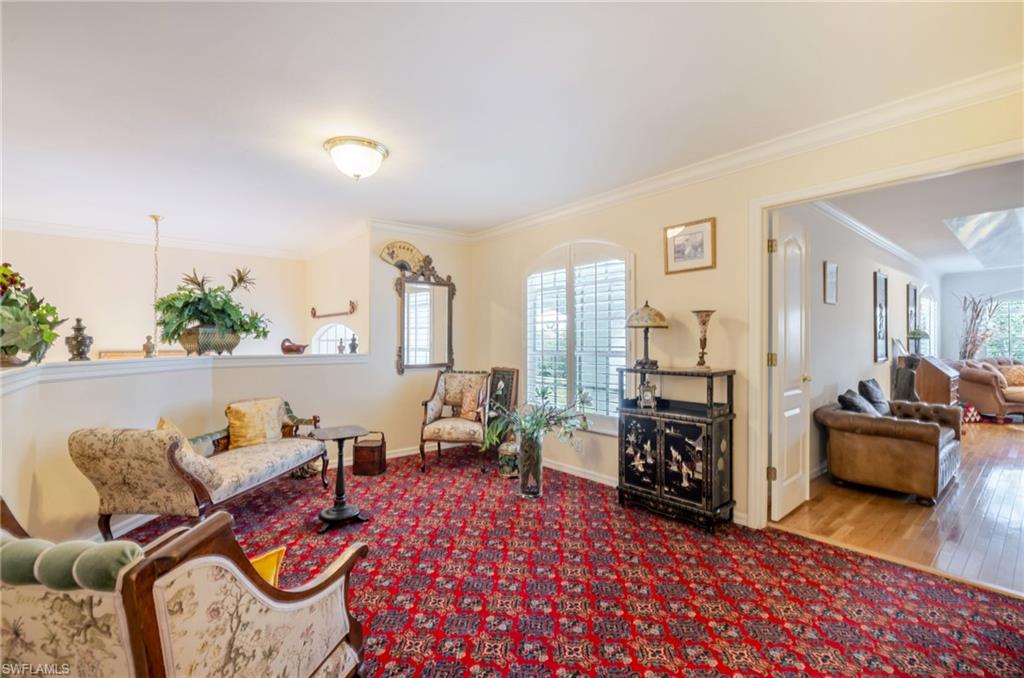Living area with crown molding, carpet flooring, and wood finished floors