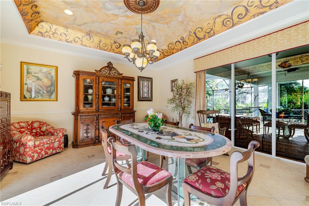 Dining area featuring a tray ceiling, light tile patterned floors, ornamental molding, and a chandelier