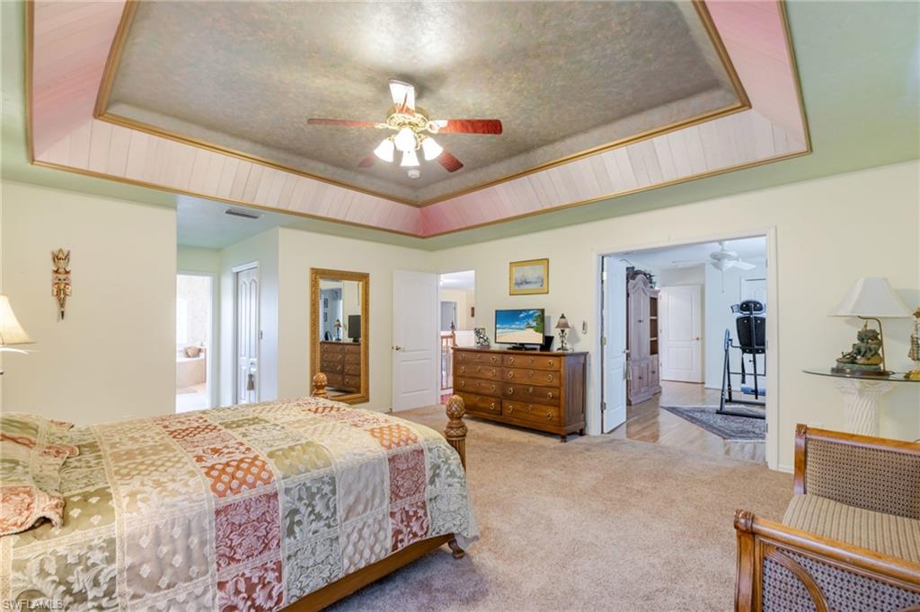 Bedroom featuring a tray ceiling, carpet flooring, and ceiling fan