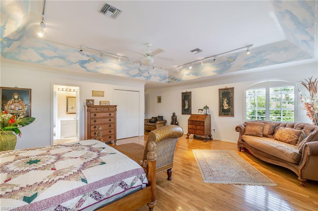 Bedroom with rail lighting, a closet, light wood-style floors, ceiling fan, and ornamental molding