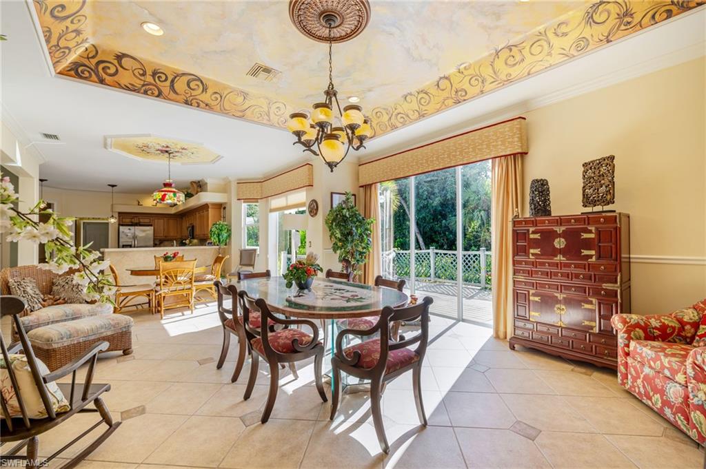 Dining area with a raised ceiling, light tile patterned floors, and crown molding