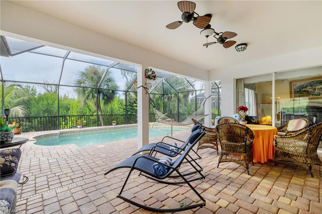 Outdoor pool with a sunroom, a patio area, glass enclosure, a ceiling fan, and outdoor dining area