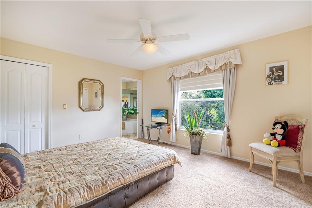 Carpeted bedroom featuring ensuite bath, a closet, and a ceiling fan