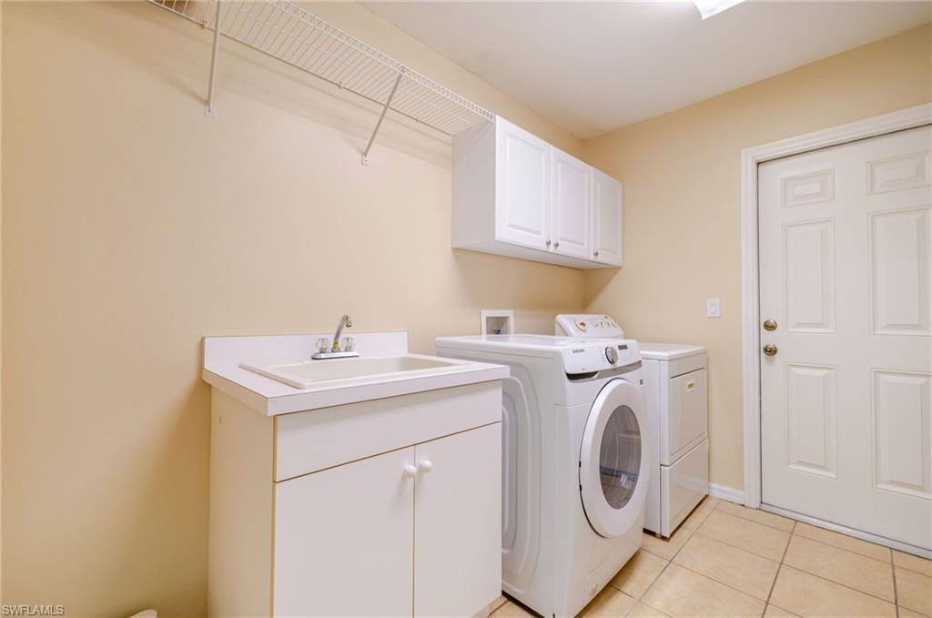 Washroom with light tile patterned floors, cabinet space, and washing machine and clothes dryer