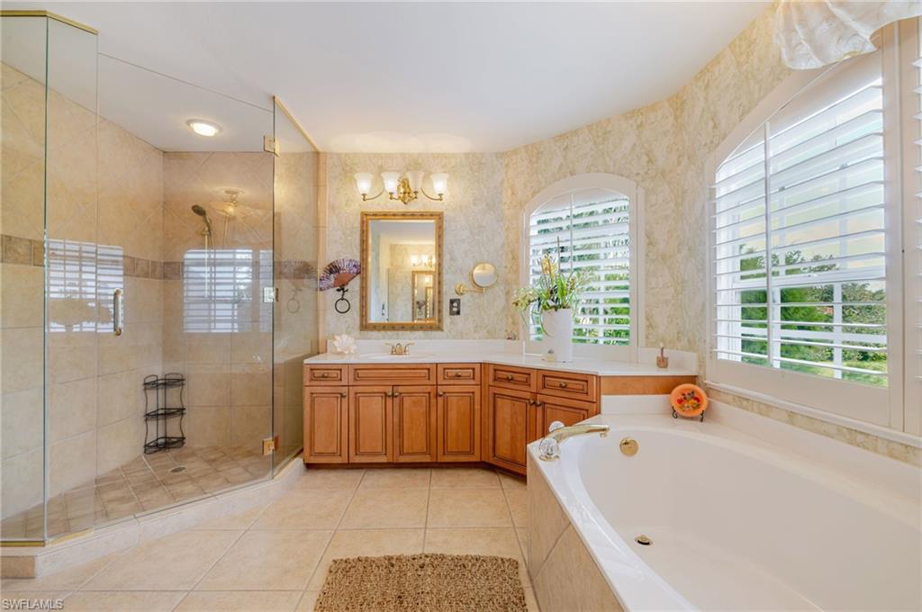 Full bathroom with a stall shower, vanity, a garden tub, light tile patterned floors, and wallpapered walls