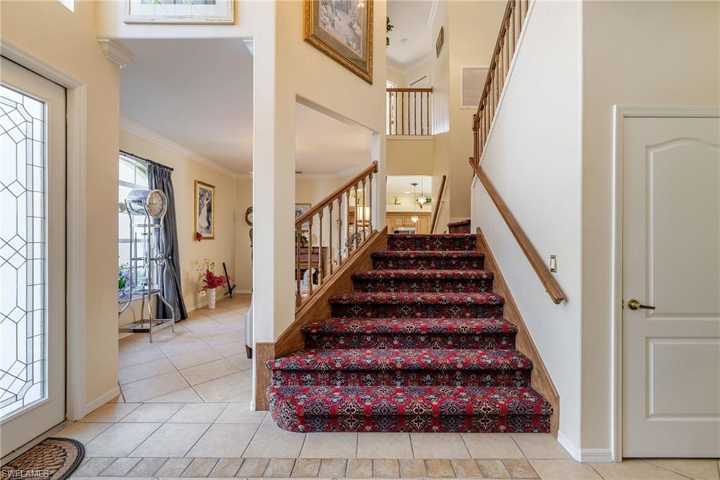 Stairway with crown molding, tile patterned flooring, and a high ceiling