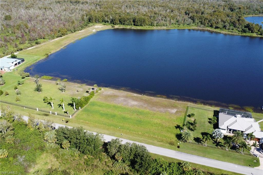Drone / aerial view of a heavily wooded area and a nearby body of water