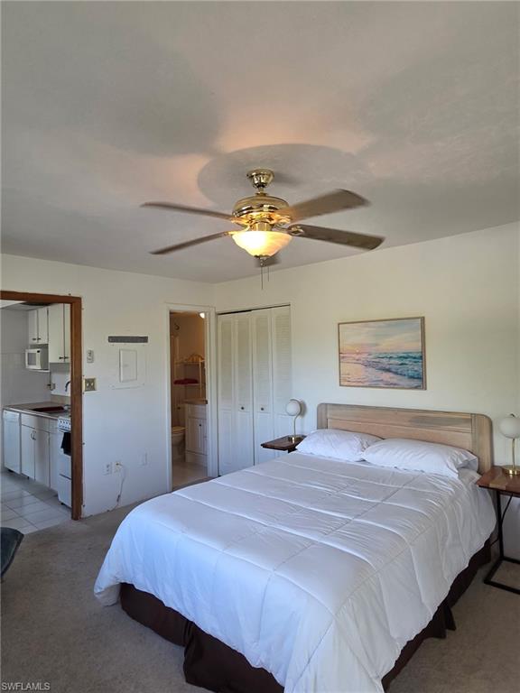 Bedroom with light colored carpet, a closet, ceiling fan, and ensuite bath