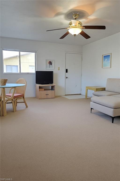 Living area with light colored carpet and ceiling fan