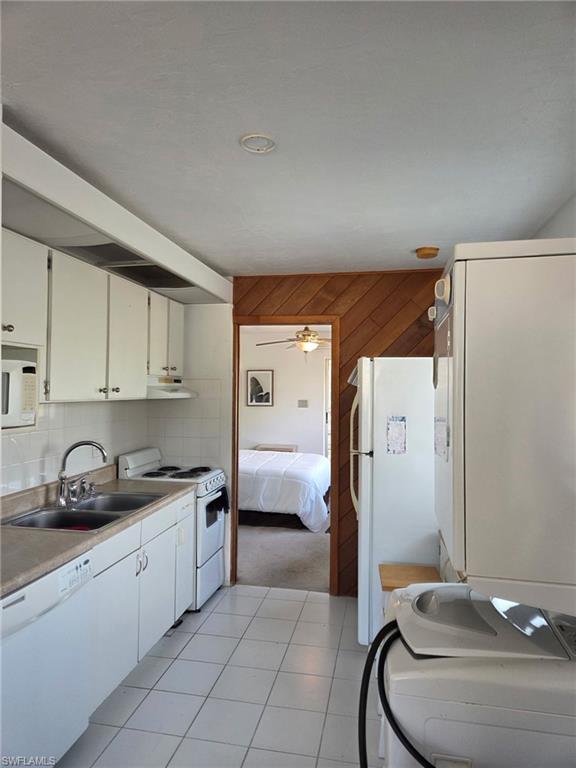 Kitchen with white appliances, light tile patterned floors, light countertops, backsplash, and white cabinets