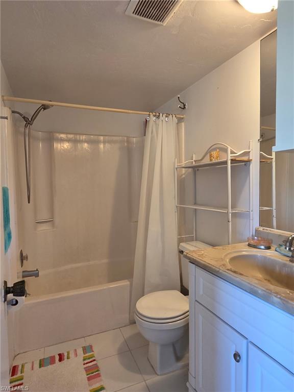 Bathroom with light tile patterned floors, shower / bath combination with curtain, and vanity
