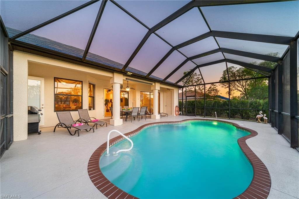 Outdoor pool featuring a sunroom, a patio, glass enclosure, and a ceiling fan