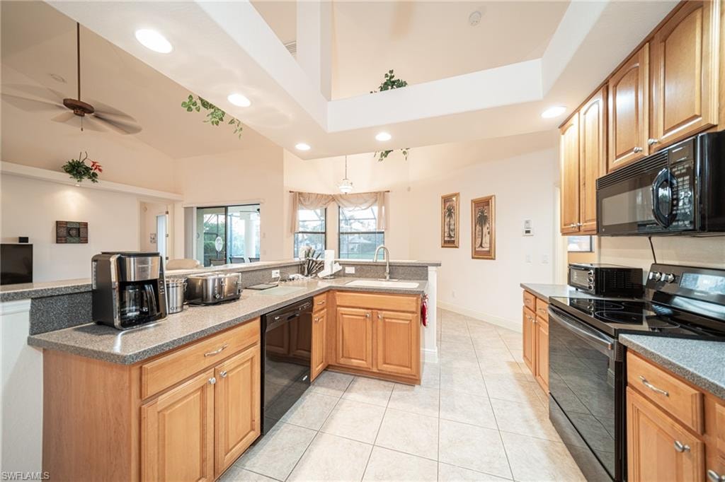 Kitchen featuring black appliances, recessed lighting, light tile patterned floors, brown cabinets, and dark stone countertops