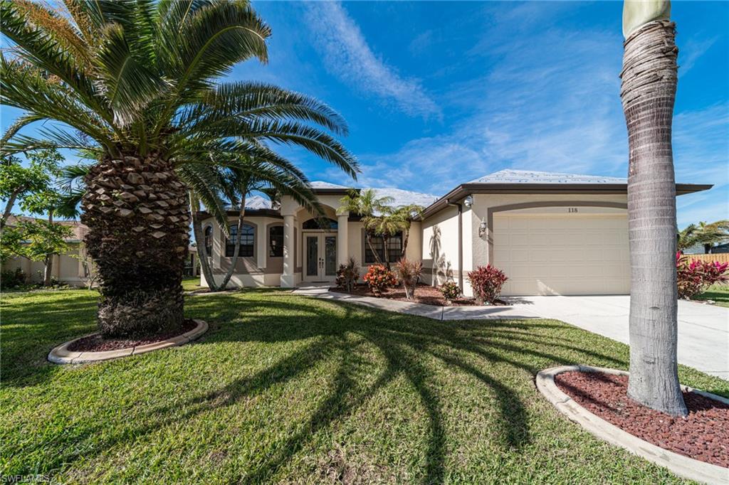 View of front of house with stucco siding, french doors, a front yard, concrete driveway, and an attached garage