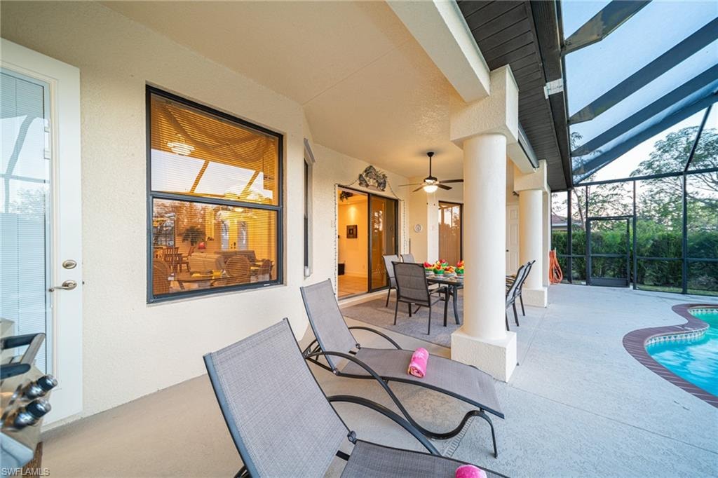 View of patio / terrace with a sunroom, glass enclosure, an outdoor pool, ceiling fan, and outdoor dining space