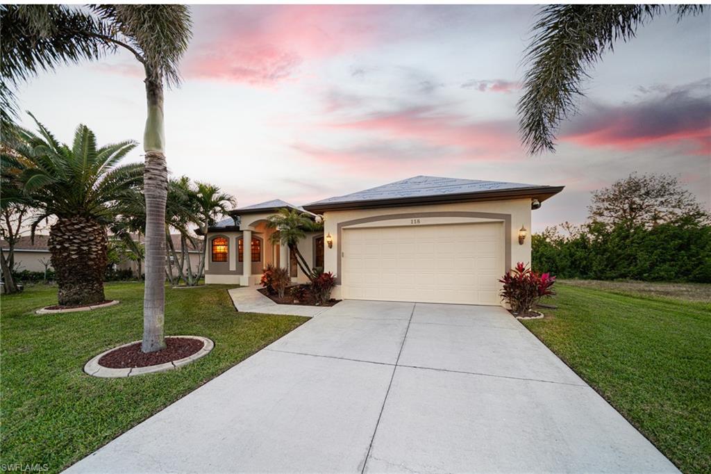 View of front of house featuring a front yard, stucco siding, concrete driveway, and a garage