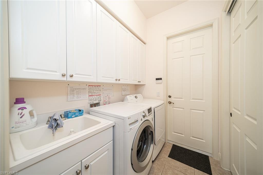 Laundry room with light tile patterned floors, separate washer and dryer, and cabinet space