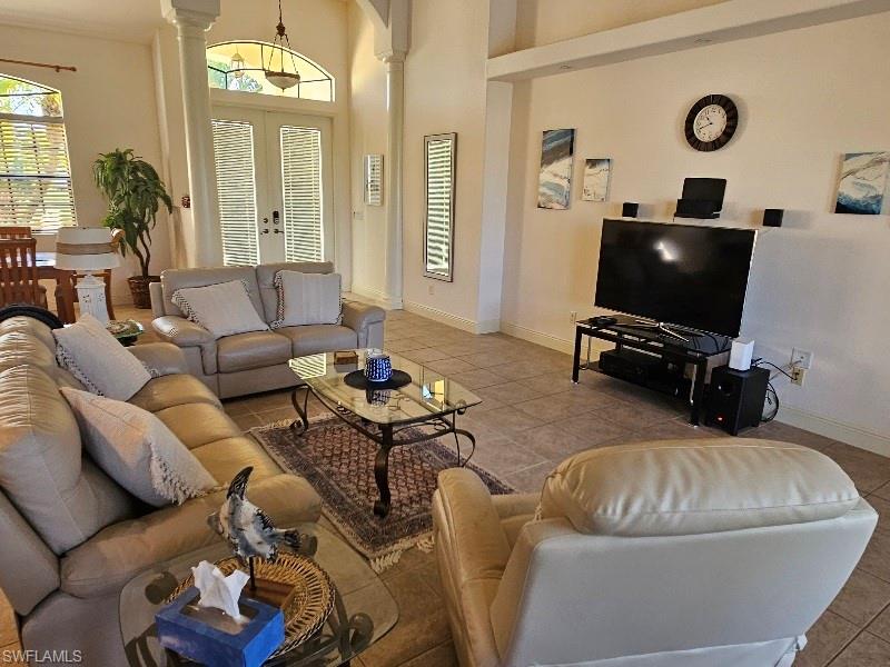Tiled living area featuring decorative columns, a high ceiling, and french doors