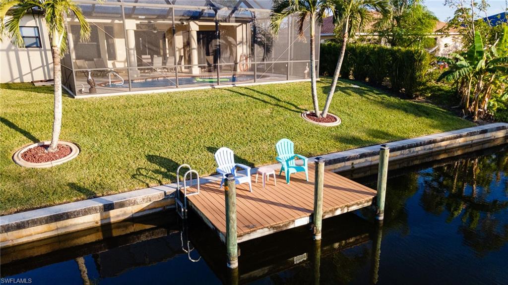 Dock area with a lawn, glass enclosure, an outdoor pool, a sunroom, and a water view