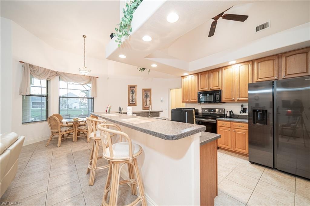 Kitchen with appliances with stainless steel finishes, a kitchen bar, recessed lighting, a kitchen island with sink, and light tile patterned floors