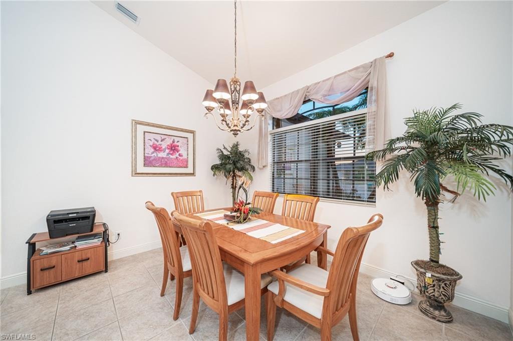 Dining room featuring light tile patterned floors, vaulted ceiling, and a chandelier