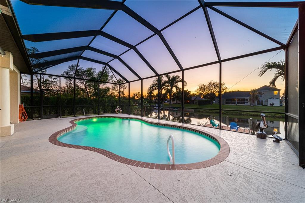 Swimming pool with a sunroom, glass enclosure, a patio, and a water view