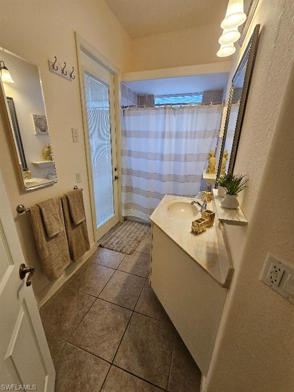 Full bathroom with vanity, dark tile patterned floors, and a shower with curtain
