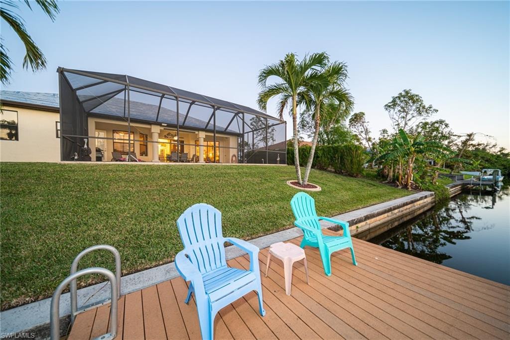 Back of house with a lanai, a sunroom, and a lawn