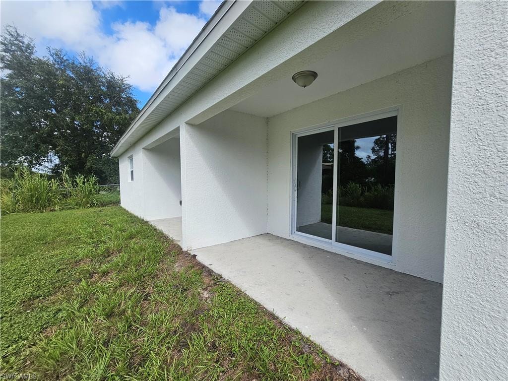 View of home's exterior featuring stucco siding, a patio area, and a yard