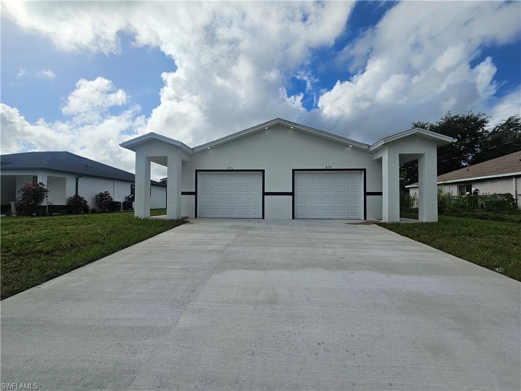 Single story home featuring a front yard, stucco siding, an attached garage, and driveway