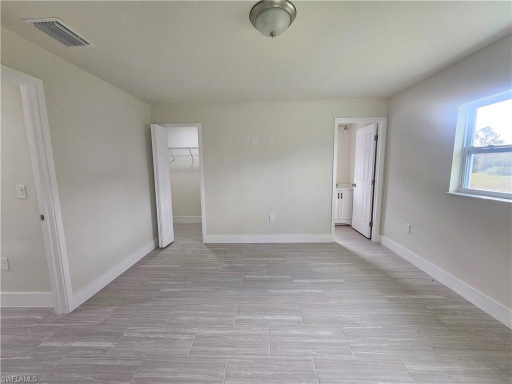 Unfurnished bedroom with a walk in closet and baseboards
