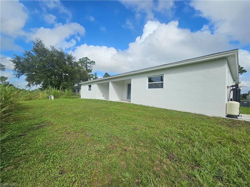Back of house featuring a patio area, a lawn, and stucco siding