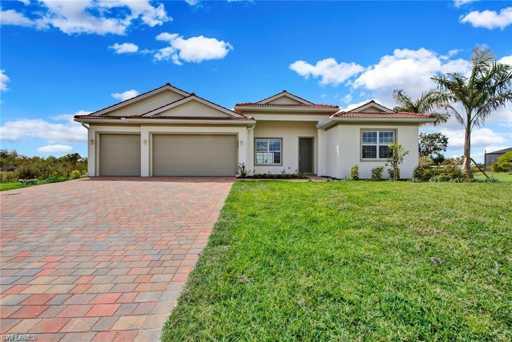 Ranch-style house featuring a front lawn, stucco siding, decorative driveway, an attached garage, and a tile roof