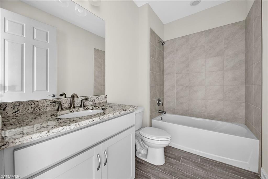 Bathroom featuring wood finish floors, bathtub / shower combination, and vanity