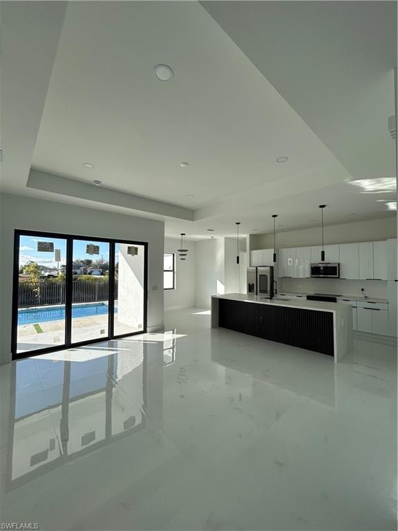 Kitchen featuring a large island, modern cabinets, pendant lighting, a raised ceiling, and freestanding refrigerator