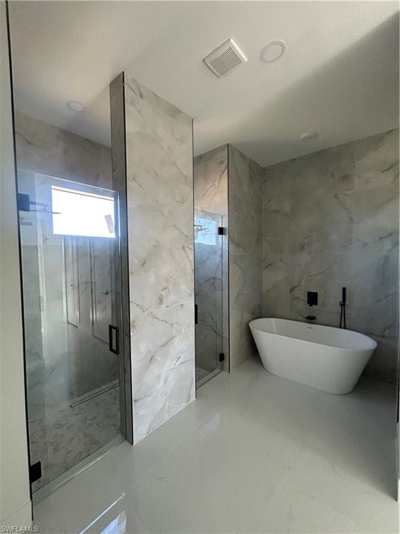 Bathroom with a soaking tub, a marble finish shower, stone wall, and marble tiled floors