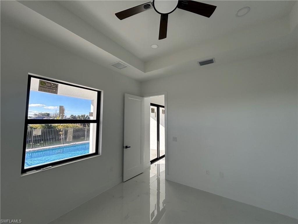 Spare room featuring a ceiling fan, a raised ceiling, recessed lighting, and concrete flooring