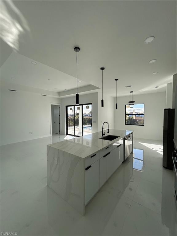 Kitchen with white cabinetry, modern cabinets, light stone counters, pendant lighting, and a large island