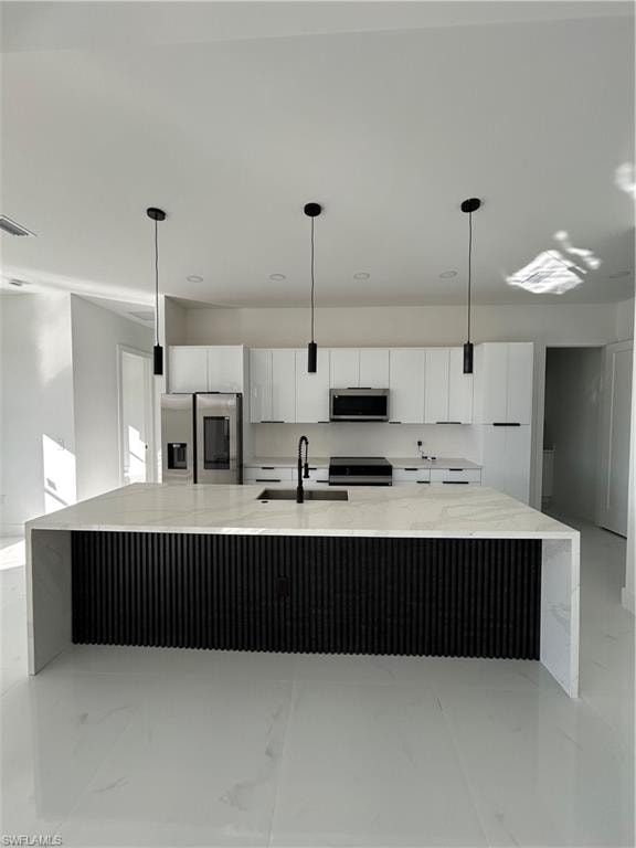 Kitchen with white cabinetry, light stone countertops, a spacious island, fridge, and hanging light fixtures