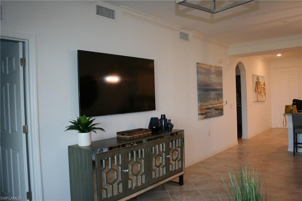 Tiled living area with ornamental molding and arched walkways