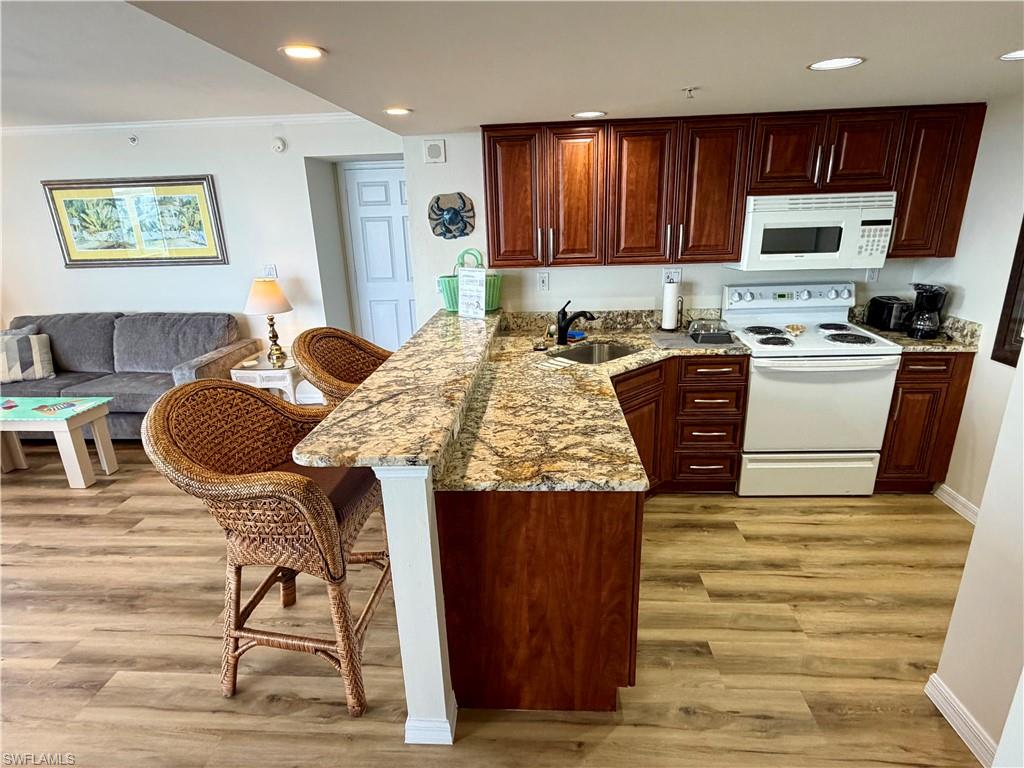 Kitchen featuring rich wood-finish cabinetry, granite countertops, and white appliances