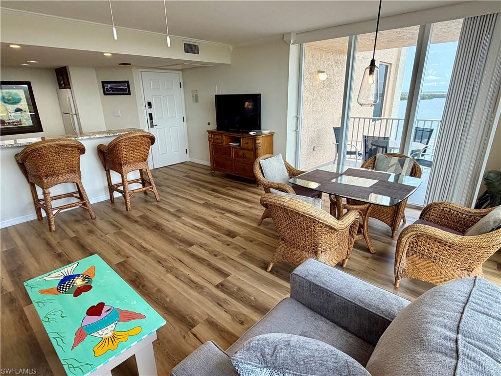 Spacious living area featuring wood-finish flooring and a breakfast bar with stone-look countertop