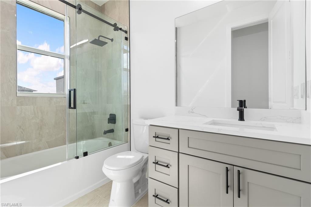 Bathroom featuring toilet, vanity, and bath / shower combo with glass door