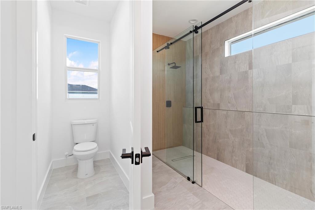 Full bath featuring toilet, a stall shower, and a wealth of natural light