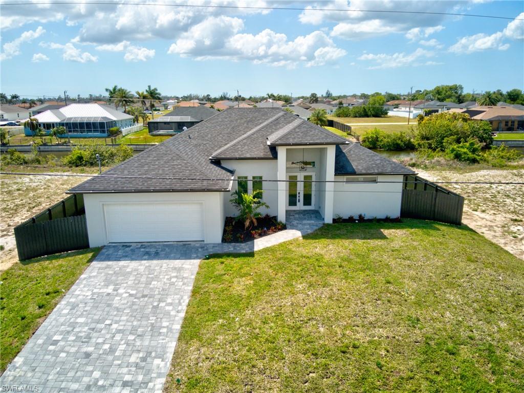 View of front of house with a garage, french doors, fence, and stucco siding