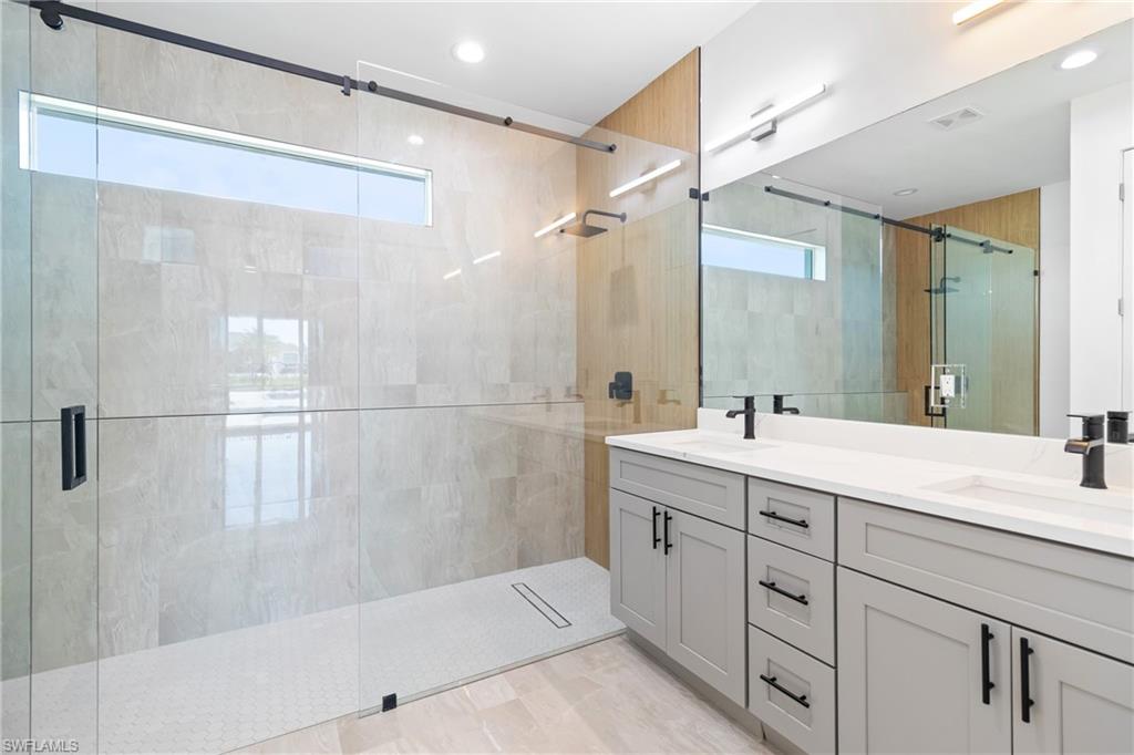 Full bathroom featuring a shower stall, double vanity, a sink, and visible vents