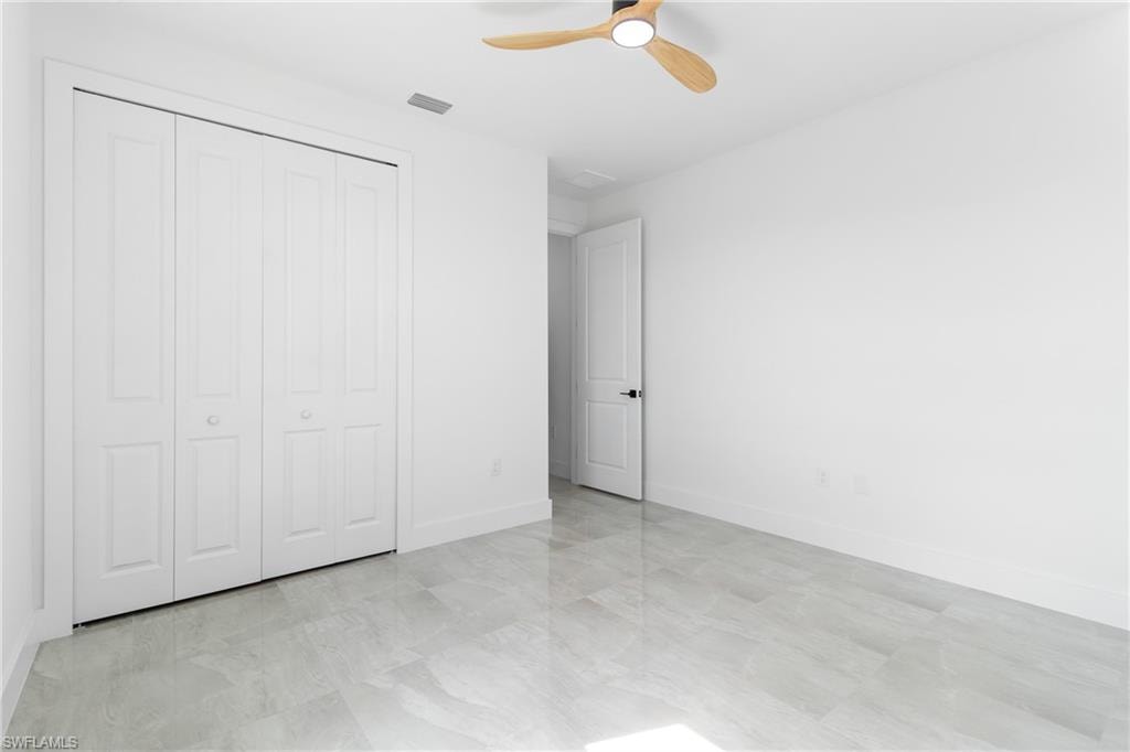 Unfurnished bedroom with a closet, ceiling fan, baseboards, and visible vents
